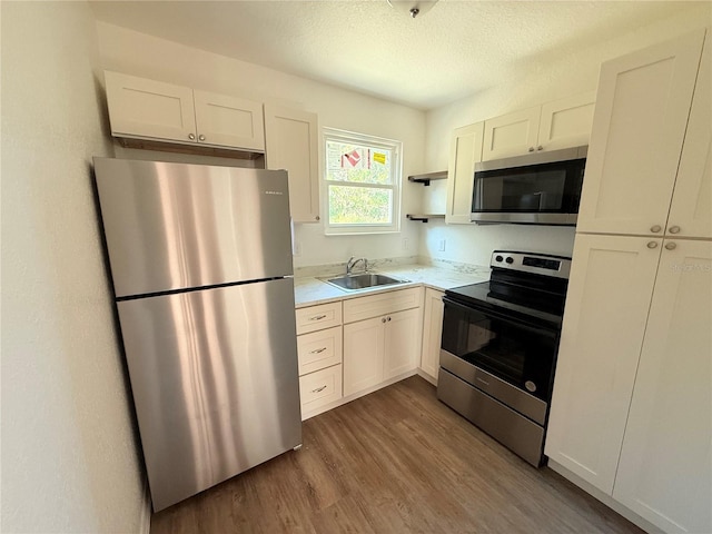 kitchen featuring white cabinetry, sink, stainless steel appliances, a textured ceiling, and hardwood / wood-style flooring