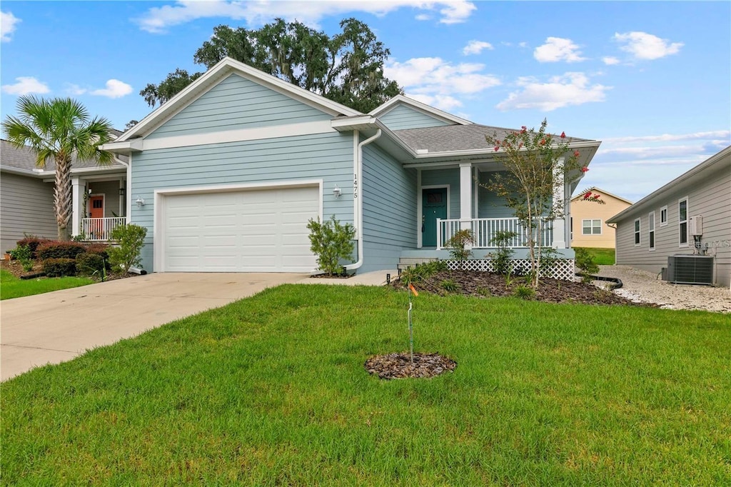 view of front facade with a front yard, central AC, a garage, and covered porch