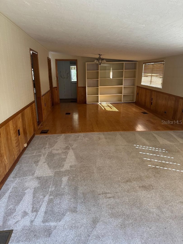 empty room with carpet, a textured ceiling, ceiling fan, and a healthy amount of sunlight