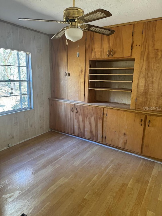 empty room featuring wood walls, light hardwood / wood-style flooring, and ceiling fan