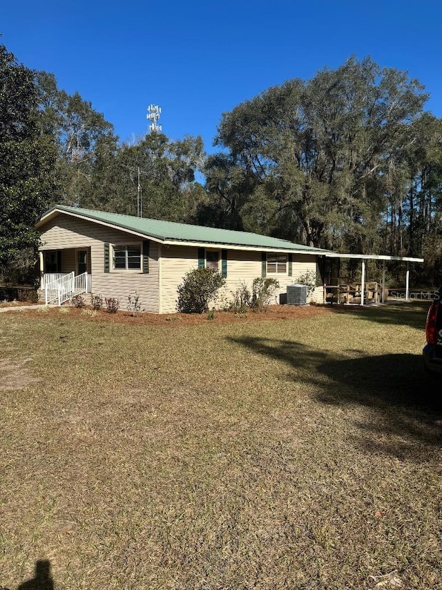 view of front of house featuring a front lawn, covered porch, central AC unit, and a carport