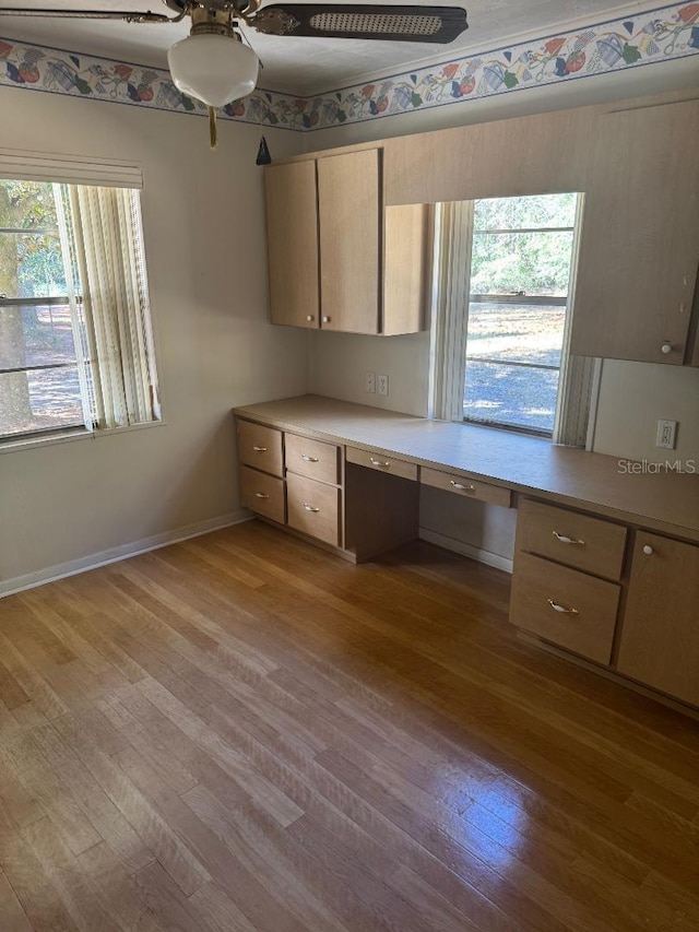 kitchen with a wealth of natural light, built in desk, light hardwood / wood-style flooring, and ceiling fan