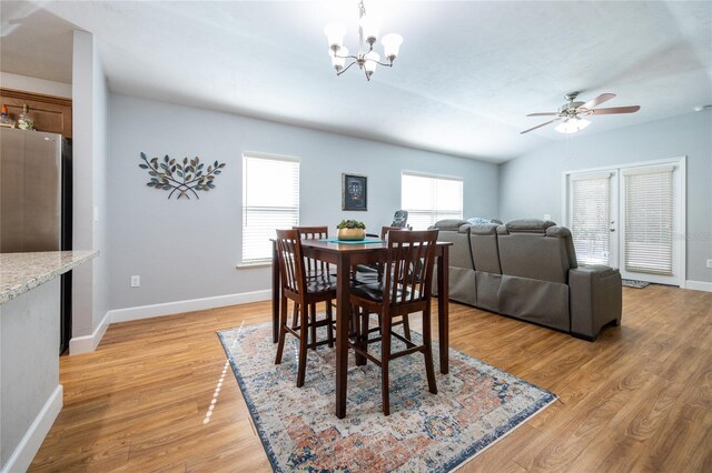 dining space featuring vaulted ceiling, light hardwood / wood-style flooring, a healthy amount of sunlight, and ceiling fan with notable chandelier