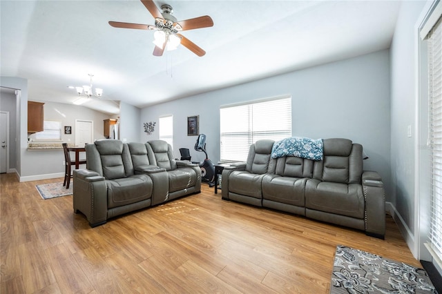 living room with lofted ceiling, light wood-type flooring, and ceiling fan with notable chandelier