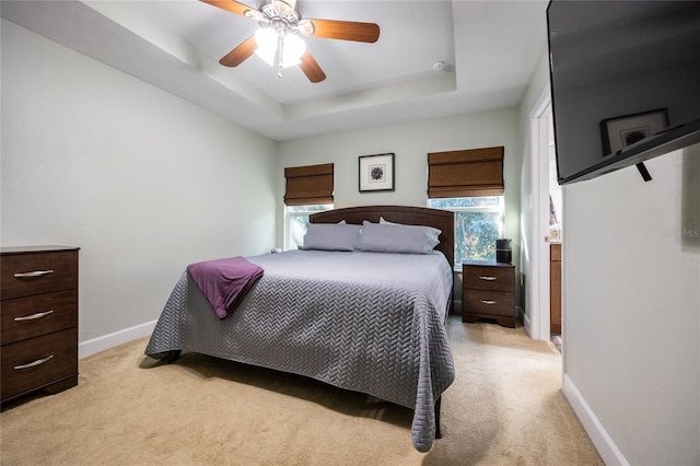 carpeted bedroom featuring a raised ceiling and ceiling fan