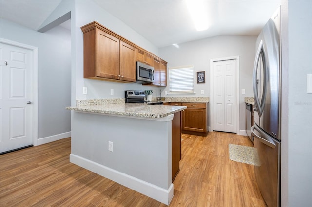 kitchen with lofted ceiling, light stone countertops, light hardwood / wood-style floors, kitchen peninsula, and stainless steel appliances