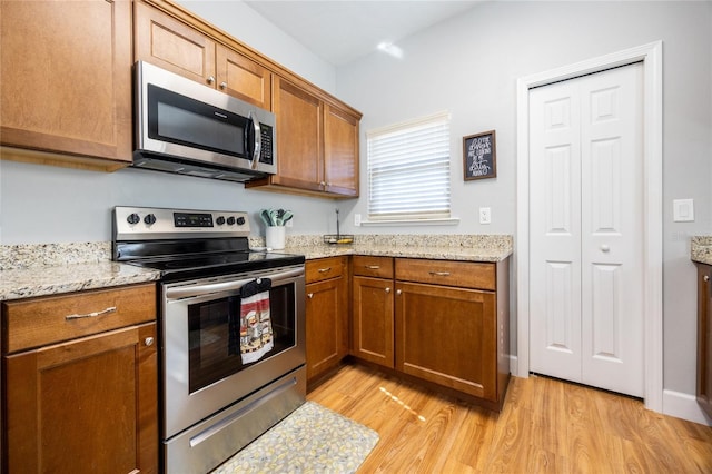 kitchen featuring light stone counters, light hardwood / wood-style flooring, and appliances with stainless steel finishes