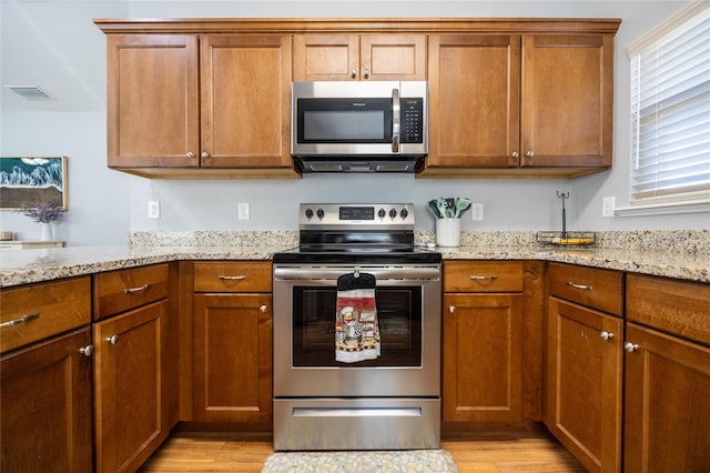 kitchen featuring light stone countertops, light wood-type flooring, and appliances with stainless steel finishes