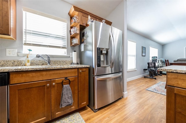 kitchen featuring sink, vaulted ceiling, light hardwood / wood-style flooring, light stone counters, and stainless steel appliances