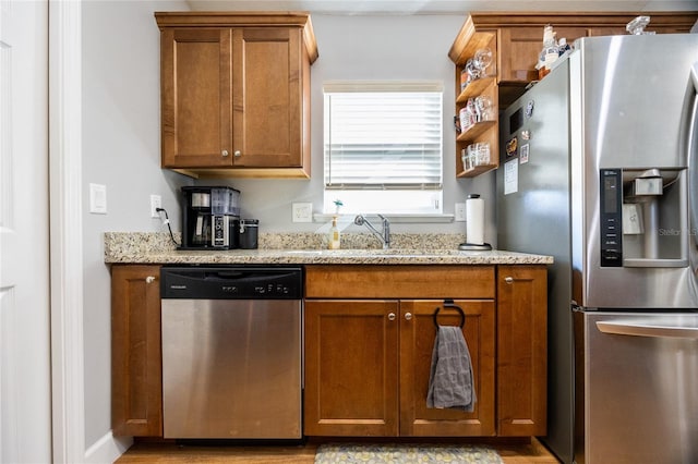 kitchen featuring light stone countertops, stainless steel appliances, and sink