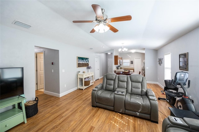 living room featuring light hardwood / wood-style flooring, ceiling fan with notable chandelier, and lofted ceiling