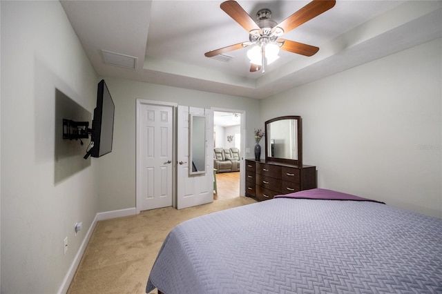 bedroom featuring light carpet, a raised ceiling, and ceiling fan