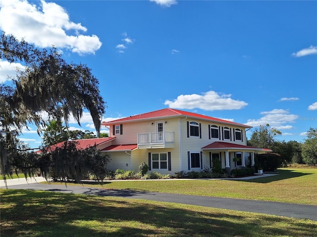 view of front of property with a balcony and a front lawn