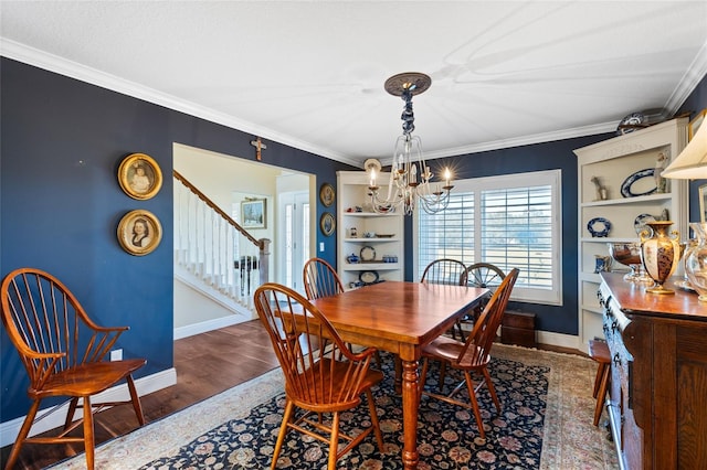 dining space featuring built in features, dark hardwood / wood-style floors, an inviting chandelier, and ornamental molding