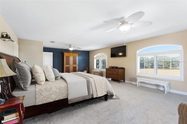 carpeted bedroom featuring multiple windows and ceiling fan