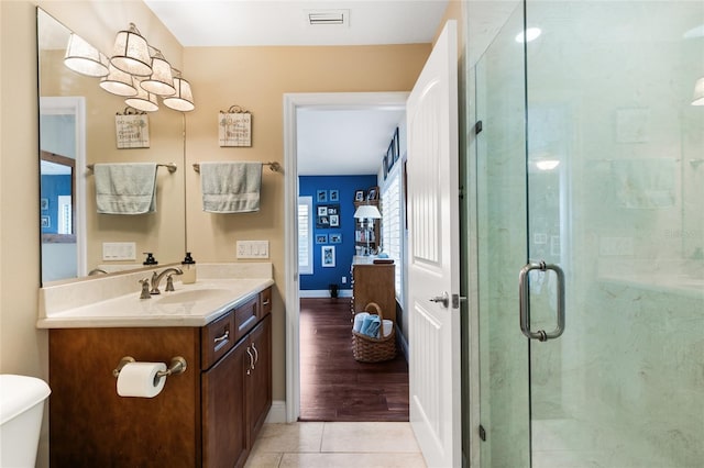 bathroom with tile patterned floors, vanity, a shower with shower door, and toilet