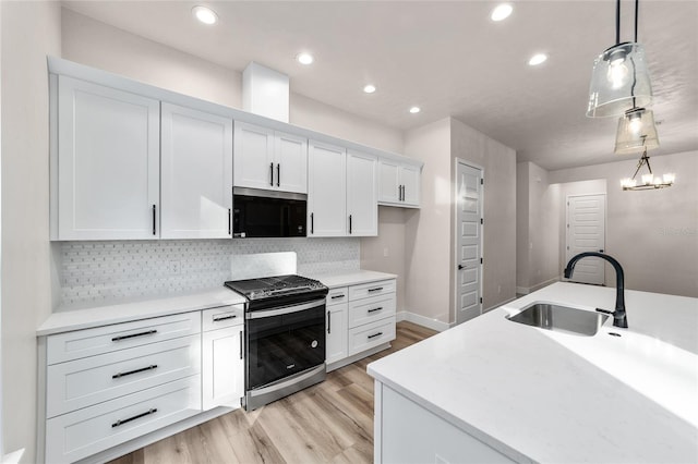 kitchen with sink, stainless steel appliances, a notable chandelier, pendant lighting, and white cabinets