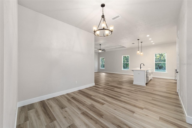 unfurnished living room with ceiling fan with notable chandelier, light hardwood / wood-style floors, and sink