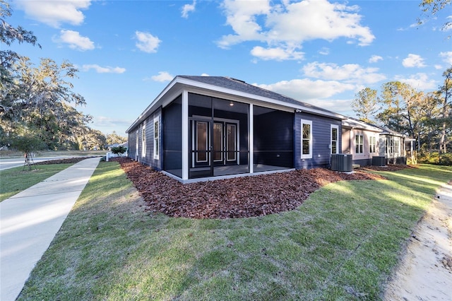 view of home's exterior with a yard, central AC unit, and a sunroom