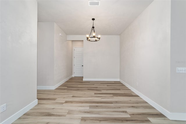 unfurnished dining area featuring light wood-type flooring and an inviting chandelier