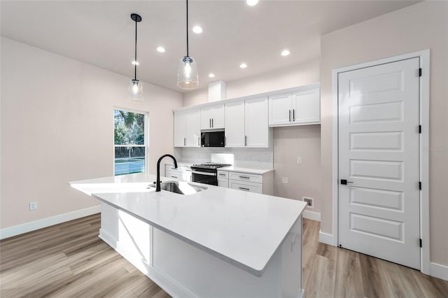 kitchen featuring white cabinetry, sink, an island with sink, and pendant lighting