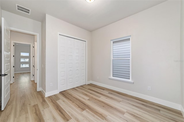 unfurnished bedroom featuring a closet and light wood-type flooring