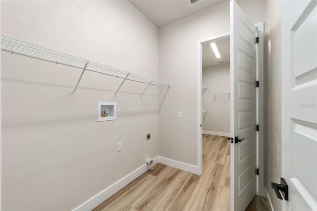 clothes washing area with hookup for an electric dryer, washer hookup, and light hardwood / wood-style flooring