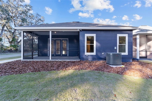 rear view of house with a yard, cooling unit, and a sunroom