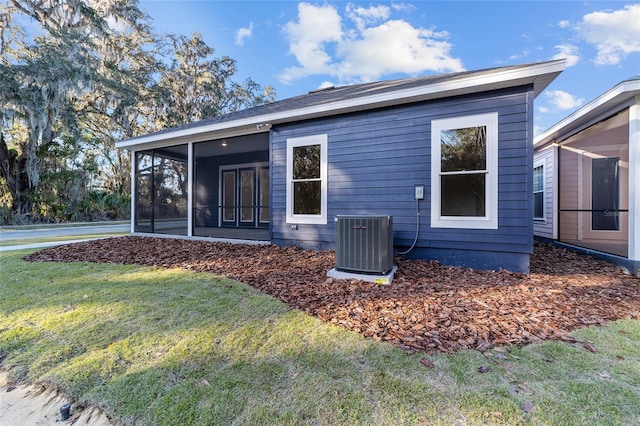 back of property with a sunroom, a yard, and cooling unit