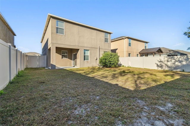 rear view of property featuring a lawn