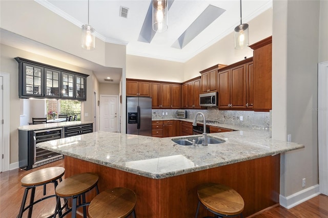 kitchen with sink, beverage cooler, stainless steel appliances, kitchen peninsula, and a breakfast bar area