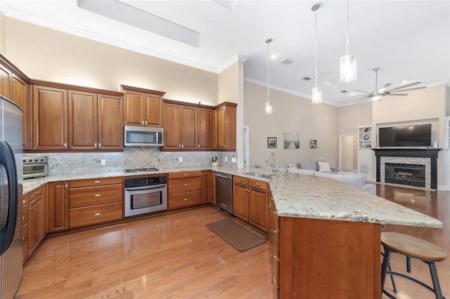 kitchen featuring ceiling fan, backsplash, pendant lighting, a breakfast bar, and appliances with stainless steel finishes