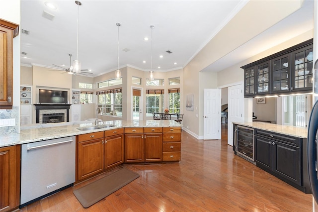 kitchen with light stone counters, stainless steel dishwasher, beverage cooler, sink, and decorative light fixtures