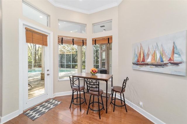 dining room with hardwood / wood-style flooring, a wealth of natural light, and crown molding