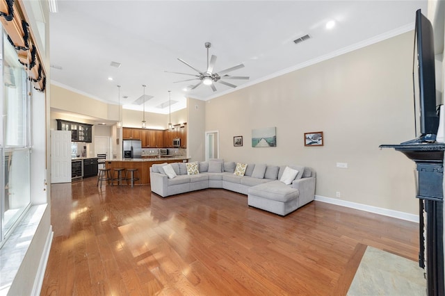 living room featuring hardwood / wood-style floors, ceiling fan, and crown molding