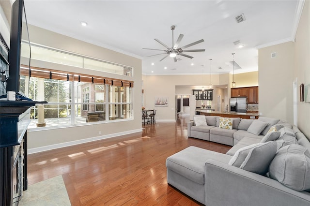 living room with hardwood / wood-style floors, ceiling fan, and ornamental molding