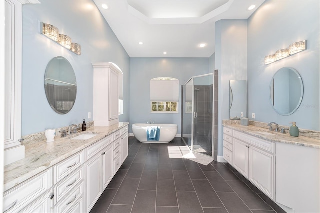 bathroom featuring tile patterned flooring, vanity, shower with separate bathtub, and a tray ceiling