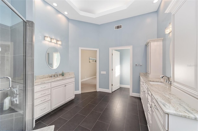 bathroom featuring vanity, a towering ceiling, walk in shower, and tile patterned flooring