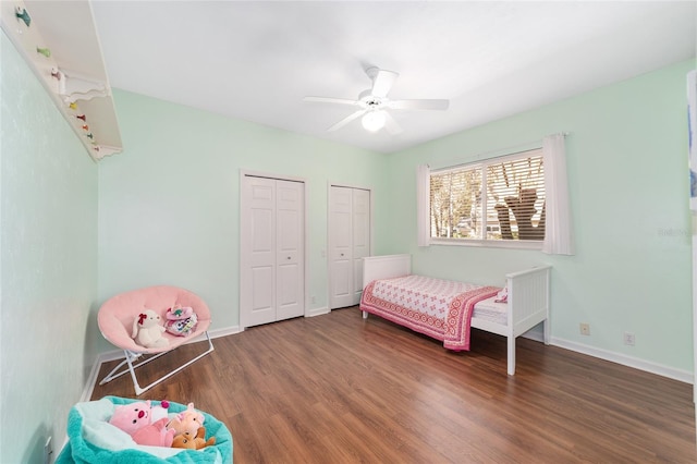 bedroom with two closets, ceiling fan, and dark wood-type flooring