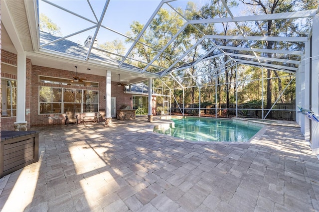 view of swimming pool with glass enclosure, ceiling fan, and a patio area