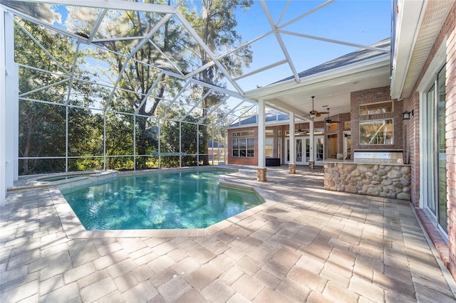 view of pool with a lanai, a patio area, french doors, and exterior kitchen