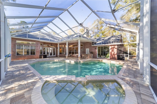 view of swimming pool with glass enclosure, ceiling fan, french doors, and a patio