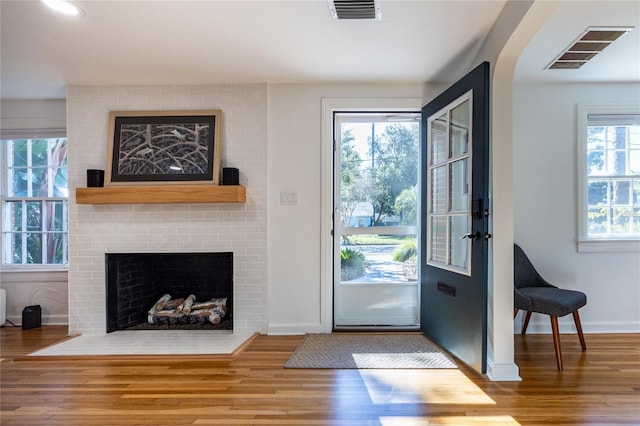 doorway to outside with a fireplace, wood-type flooring, and plenty of natural light