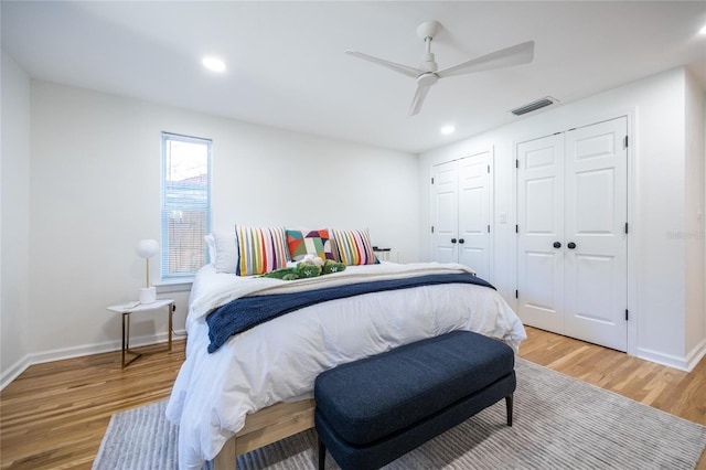 bedroom featuring ceiling fan, wood-type flooring, and two closets