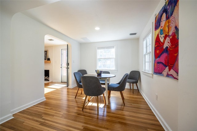 dining room featuring hardwood / wood-style flooring and a brick fireplace