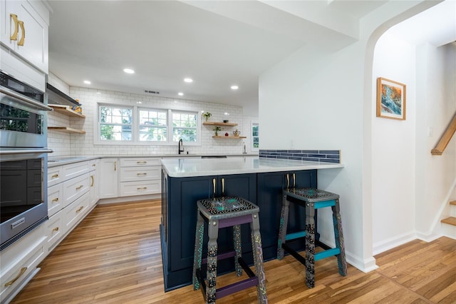 kitchen with a kitchen breakfast bar, white cabinetry, kitchen peninsula, and tasteful backsplash