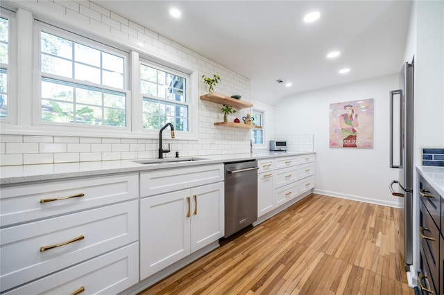 kitchen featuring white cabinetry, sink, light stone counters, light hardwood / wood-style flooring, and decorative backsplash