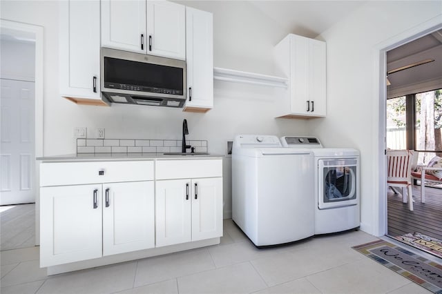 laundry area with washer and clothes dryer, light tile patterned flooring, cabinets, and sink