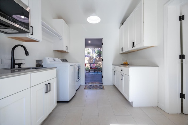 clothes washing area with cabinets, light tile patterned floors, washer and dryer, and sink