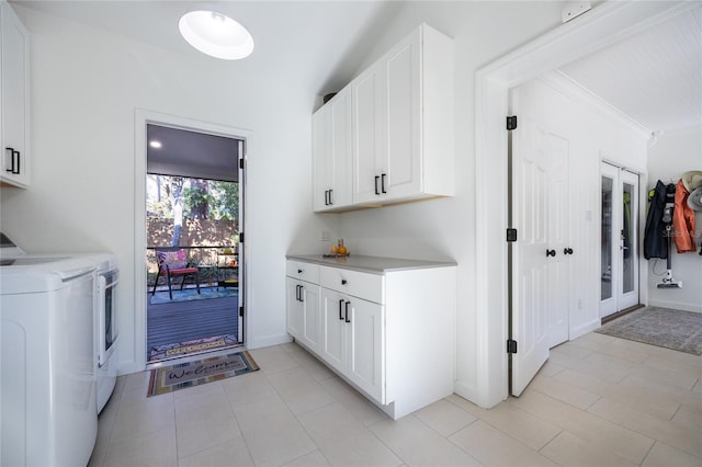 clothes washing area featuring cabinets, light tile patterned floors, and washing machine and clothes dryer